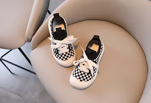 Close-up of black and white checkerboard canvas kids sneakers with white rubber soles