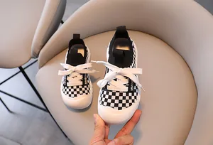 Detailed macro view of kids' checkerboard sneakers featuring rubber toe cap and side logo