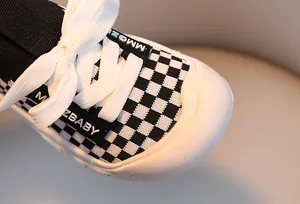 Close-up of kids checkered sneakers featuring white rubber toe cap and flat cotton laces