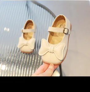 Close-up of cream Mary Jane girl shoe with soft rubber sole and large bow detail