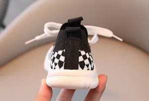 Close-up of kids knitted sports shoe heel featuring checkerboard pull tab and thick sole