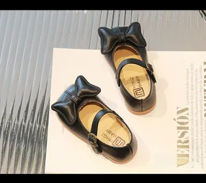 Close-up of black Mary Jane girls' shoes featuring a large bow and non-slip rubber sole