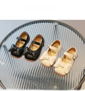 Detail of girls' Mary Jane shoes with stylish bows and durable rubber soles in beige and black