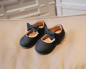 Detail of baby Mary Jane shoes with black lychee pattern leather and bow ornament