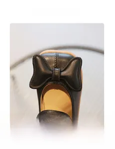 Macro detail of girls' black leather princess shoes with a soft bow and square toe