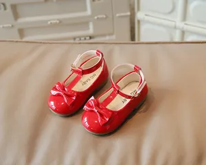 Dettaglio delle scarpe Mary Jane in pelle verniciata rossa con cinturino a T e fiocco