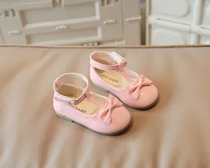 Dettaglio scarpe in pelle verniciata rosa per bambine con fiocco e fibbia a T dorata