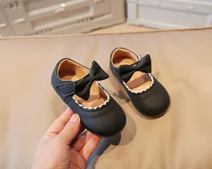 Detail of toddler girl Mary Jane shoes with black leather texture and cute bow decoration