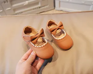 Macro detail of brown leather toddler shoe with bow and white scalloped edge trim