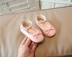 Dettaglio di scarpa rosa in vernice per bambina con fiocco e cinturino a T