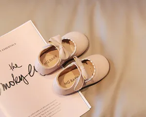 Close-up of baby girl pink leather princess shoes with a cute bow and wavy edge detail