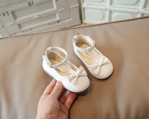 Dettaglio di scarpe Mary Jane in vernice bianca con cinturino a T e chiusura con fiocco