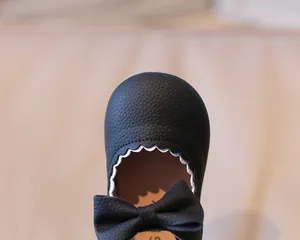 Close-up of black Mary Jane shoes with pebbled leather texture and white scalloped trim