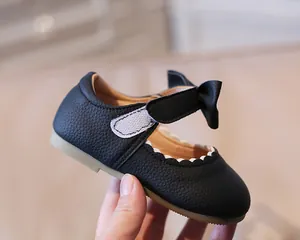 Macro shot of black litchi grain leather baby shoes with cute bow and wavy edge details