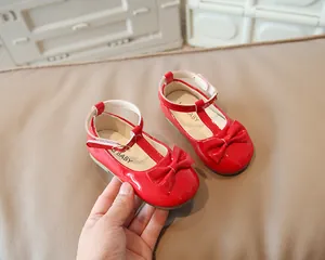 Dettaglio di scarpe Mary Jane in vernice rossa per bambina con fiocco grande e cinturino