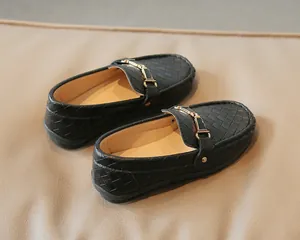 Gros plan de mocassins noirs tressés pour enfants avec boucle mors de cheval dorée