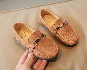 Détail de mocassins marron tressés pour enfants avec boucle élégante noir et doré