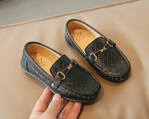 Détail de mocassins noirs tressés pour enfants avec boucle dorée et semelle en cuir souple