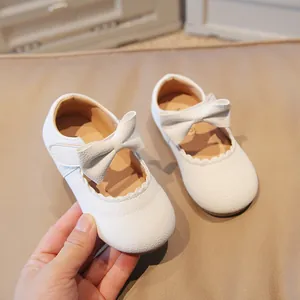 White baby girl Mary Jane shoes with bow decoration and scalloped edges in pebbled texture