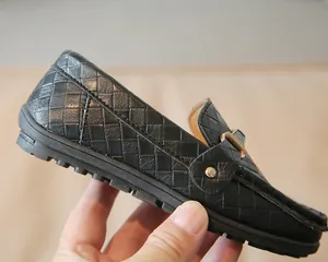 Détail de mocassins en cuir tressé noir avec boucle dorée et semelle à picots
