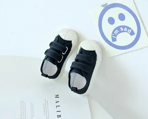 Détail de chaussures en toile noire pour enfants avec double scratch et bout en caoutchouc