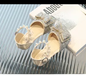 Détail de chaussures de princesse à paillettes argentées pour filles avec nœud et perle