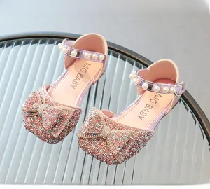 Détail d'une chaussure fille à paillettes roses avec nœud strass et bride perle cheville