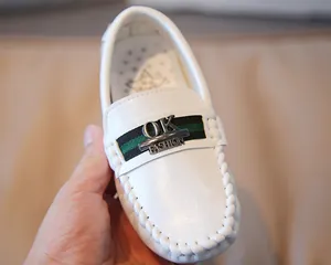 Nahaufnahme weißer Leder-Loafer für Kinder mit grün-schwarzem Band und Metallschnalle