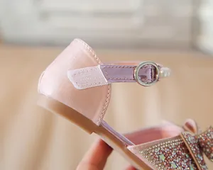 Détail de chaussure princesse en soie rose avec étoiles en strass, perle et velcro