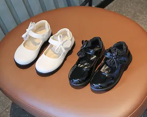 Close-up of shiny patent leather Mary Jane shoes with bows in black and white colors