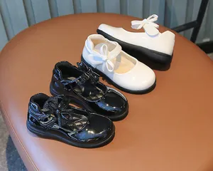 Detail of girls' Mary Jane shoes with bow velcro straps in black and white glossy finish