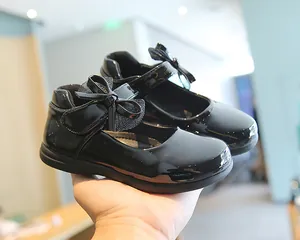 Close-up of black patent leather Mary Jane shoes with glitter bow and velcro strap