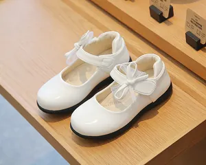 Detail of girls' white Mary Jane shoes featuring glossy finish and mesh bow decoration