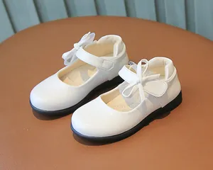 Close-up of white girls' Mary Jane shoes with patent leather finish and bow detail