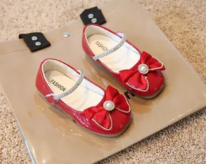 Détail de chaussures Mary Jane rouges en cuir verni pour fille avec nœud et perle