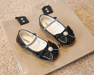 Détail de chaussures Mary Jane en cuir verni noir avec nœuds en strass et perles