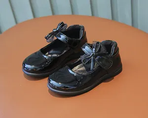 Close-up of black patent leather girls Mary Jane shoes with delicate bow and Velcro strap
