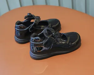 Detailed view of black patent leather girls Mary Jane shoes with a bow and velcro strap