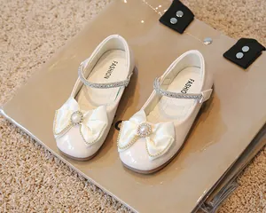 Détail de chaussures Mary Jane crème avec nœud en satin, perles et strass brillants
