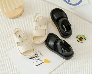 Vue à plat de sandales pour enfants en noir et crème avec brides en cuir souple