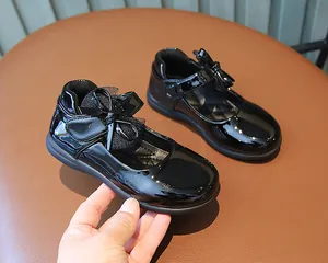 Detail of black patent leather girls Mary Jane shoes with elegant bow decoration