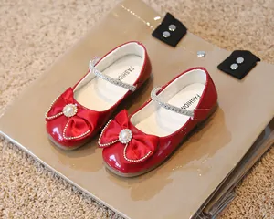 Détail de chaussure Mary Jane rouge avec nœud en satin, perles et strass scintillants