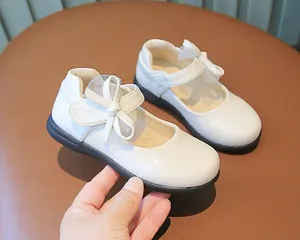 Detailed macro view of white patent leather Mary Jane shoes with mesh bow and velcro strap