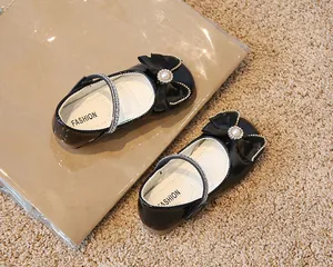 Détail de chaussures Mary Jane en cuir verni noir avec nœud perlé et bride brillante