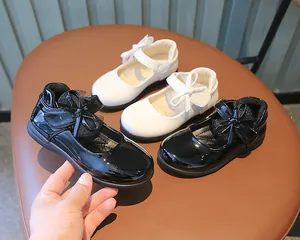 Top view of shiny patent leather Mary Jane shoes with bows in black and white colors