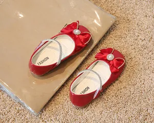 Détail de chaussures Mary Jane rouges avec nœud en satin, perle et boucle en strass