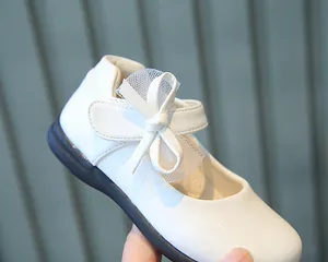 Close-up of white patent leather girl's Mary Jane shoes with mesh bow and velcro strap