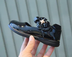 Détail de chaussures Mary Jane noires en cuir verni pour filles avec fleur en perles et strass