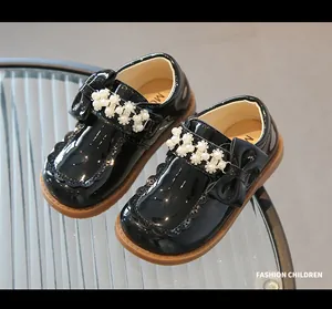 Close-up of girls' black patent leather shoes with pearl bow and rubber sole detail