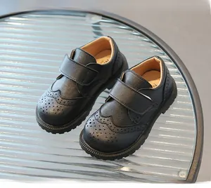 Close-up of kids black leather brogue shoes with velcro straps and hollowed details
